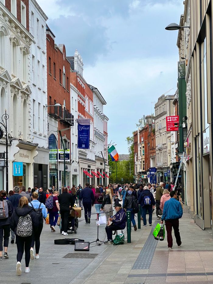 Busy Grafton Street in Dublin bustling with people and street performers on a lively day.