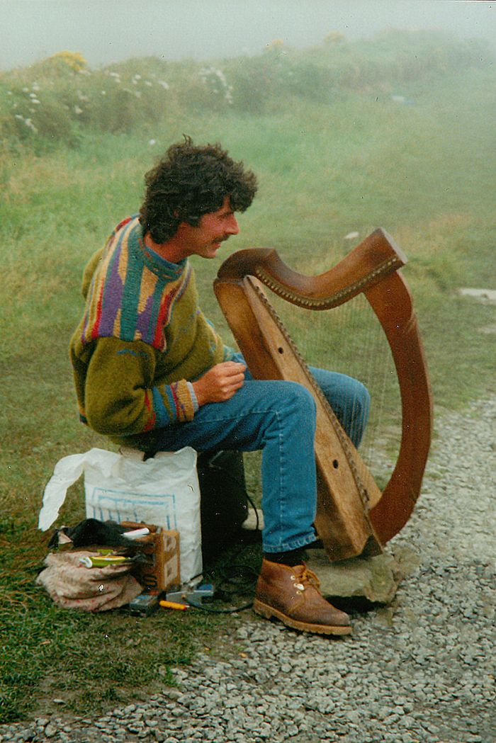 Authentic Irish musician playing harp outdoors in County Clare, Ireland.
