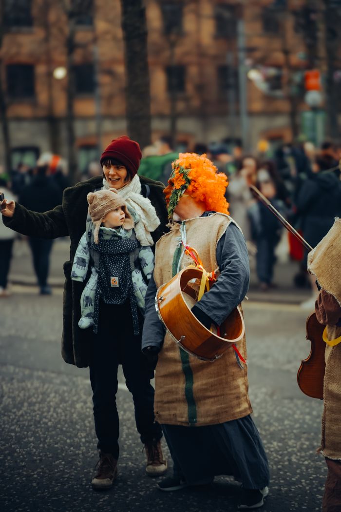 Vibrant street scene from a festive parade in Belfast, featuring people in colorful costumes and cheerful mood.
